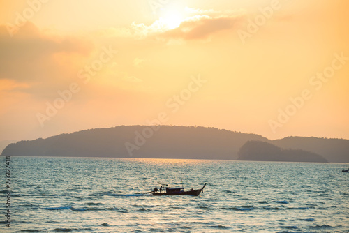 Beautiful sea landscape with small boat, blue coast and colorful sunset with bright sun © Pavlo Vakhrushev