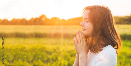 Valokuva Teenager Girl closed her eyes, praying in a field during beautiful sunset