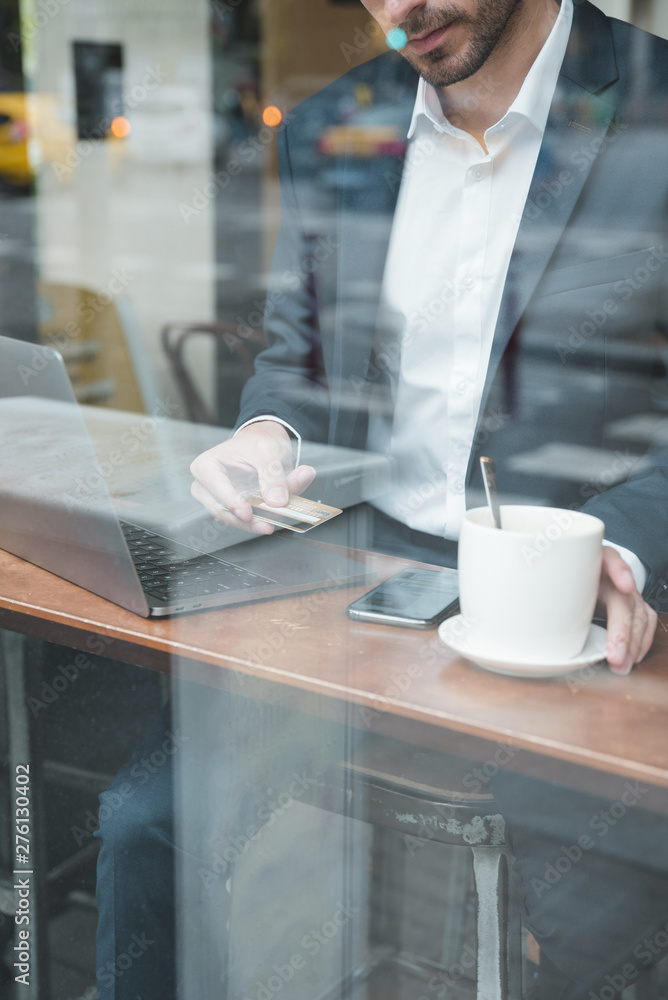 Young businessman using credit card to pay bill in cafe