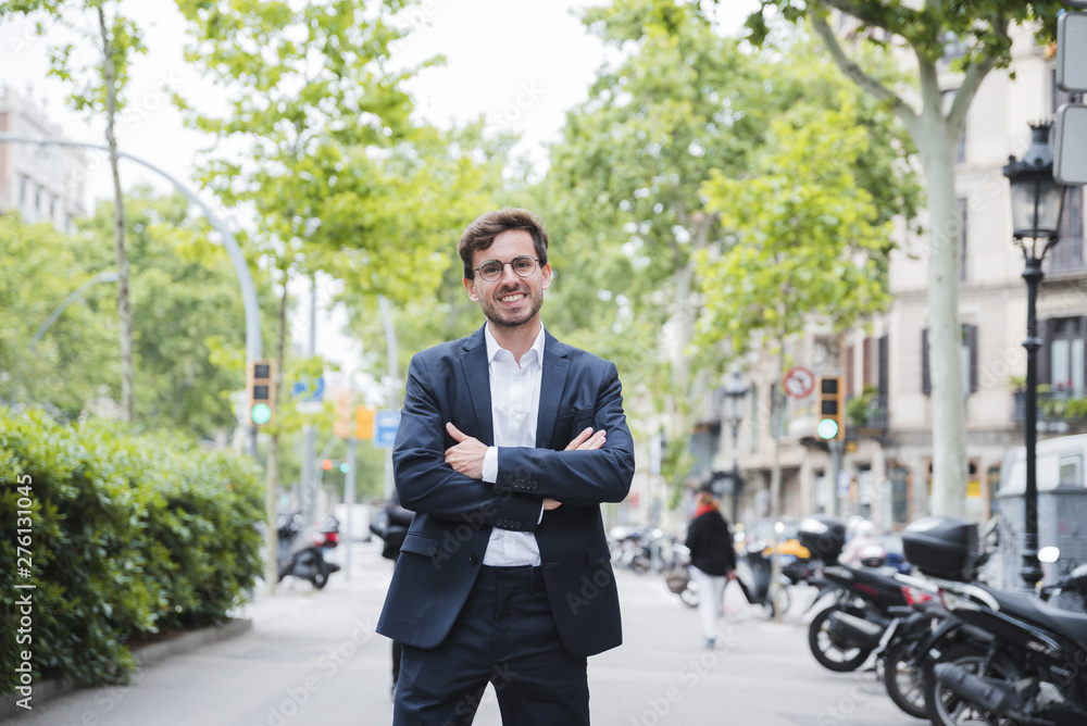 Young businessman standing on street with his arm crossed looking at camera Young businessman standing on street with his arm crossed looking at camera