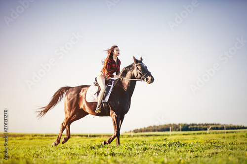 Woman riding a horse on a grass field.