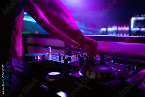 DJ turntable console mixer controlling with two hand in concert nightclub stage.