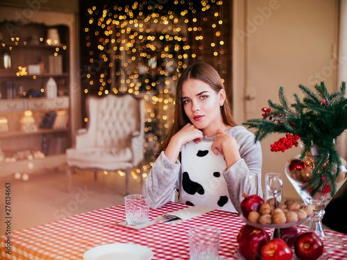 Smiling beautiful woman sitting at home near christmas tree photo