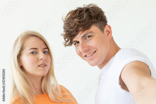 Charming young couple cute blond girl girl take a selfie posing over white background. Concept a young couple of teenagers or millennials In love.