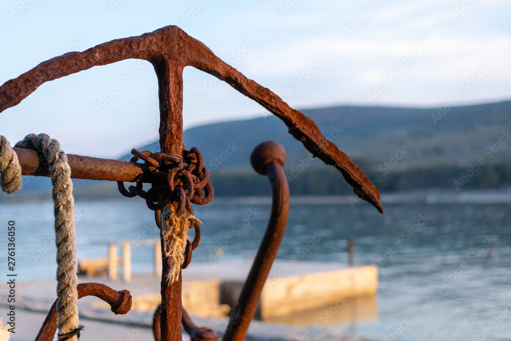 Fototapeta premium rusty old anchor with rope in the evening sun