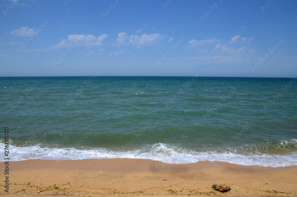 Seashore in summer, with clouds in the sky, with waves