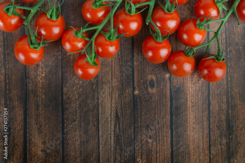 Fotografie Many fresh cocktail tomatoes on a panicle, wooden background and copy space