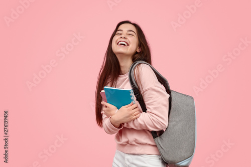 Photo Excited student laughing and hugging notebooks