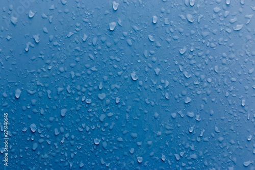 Clear water drops on a blue surface. Abstract background.