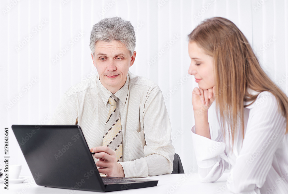 two members of the company sitting behind a Desk two members of the company sitting behind a Desk