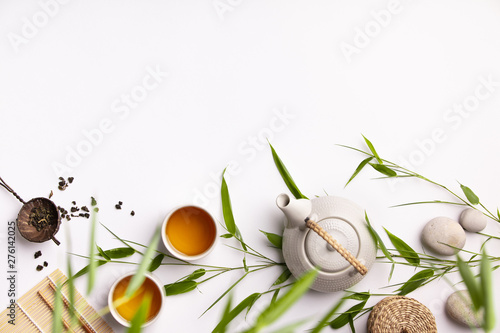 Asian food background set with green tea, cups and teapot with bamboo branches