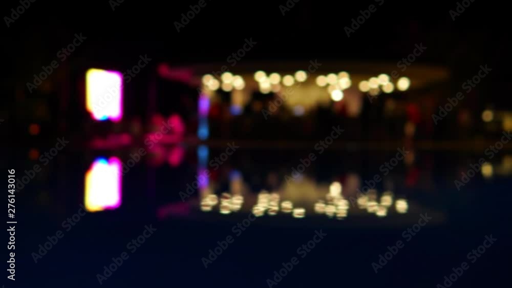 Blurred, defocused night pool party. Color lights reflections in the pool surface. Round bokeh. Beautiful background. Blurred, defocused night pool party. Color lights reflections in the pool surface. Round bokeh. Beautiful background.