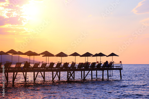Silhouette of umbrellas and deck chairs on sunset sky background, Turkey