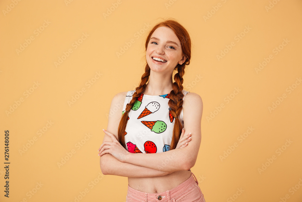 Excited beautiful redhead woman dressed in ice cream printed t-shirt posing isolated over yellow background. Excited beautiful redhead woman dressed in ice cream printed t-shirt posing isolated over yellow background.