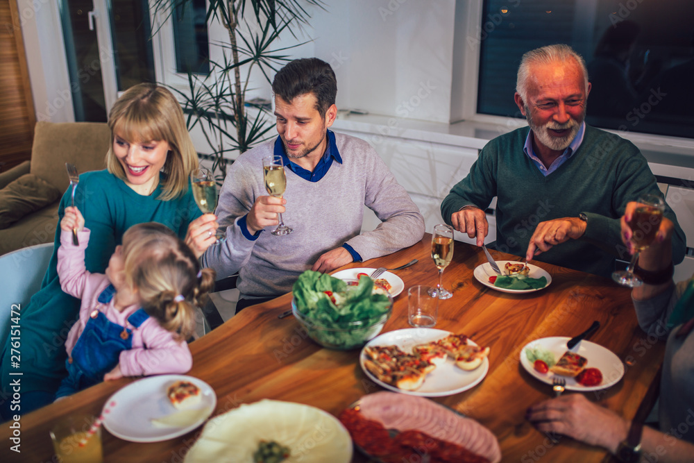 Multi generation family enjoying meal around table at home