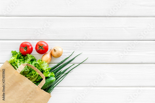 Buying fresh vegetables in paper bag on white wooden background top view copyspace