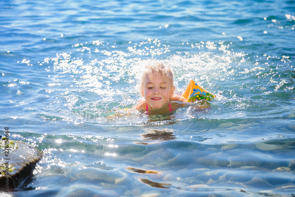 Child with inflatable ring on beautiful beach. Little girl swimming in exotic sea. Ocean vacation with kid. Children play on summer beach. Water fun. Kids swim. Family holiday on tropical island.