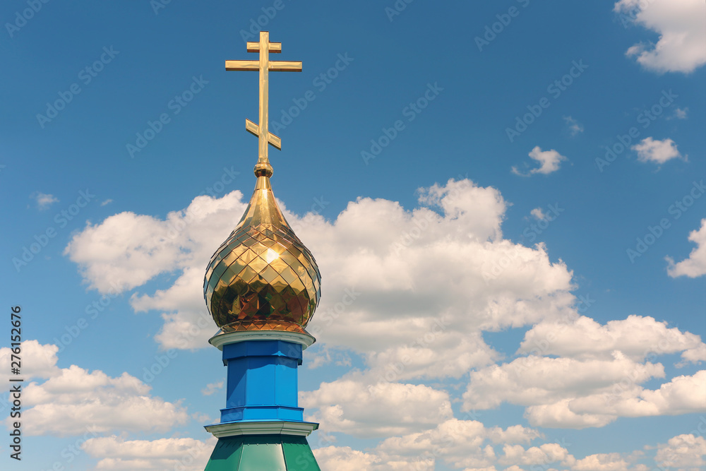 Gilded dome of church against the blue sky and white clouds.