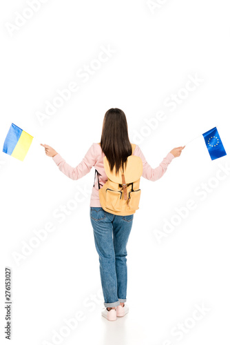 full length view of student with backpack holding Ukrainian and European flags isolated on white