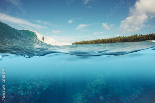 half underwater shot of surfer surfing a wave