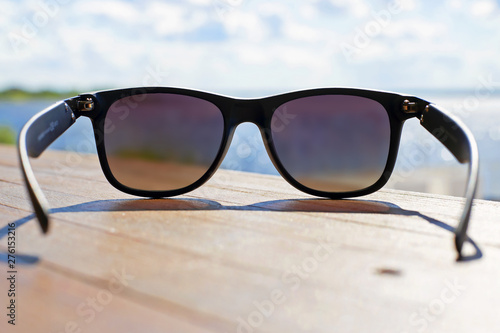fashion sunglasses in sunlight on a wooden surface on the background of the sea