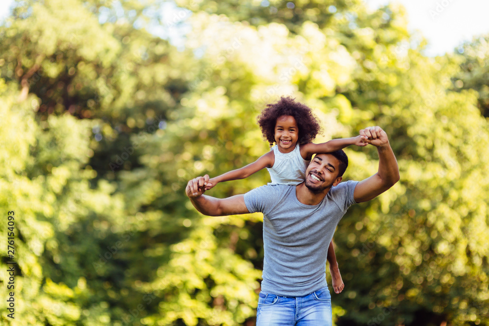 Portrait of young father carrying his daughter on his back Portrait of young father carrying his daughter on his back