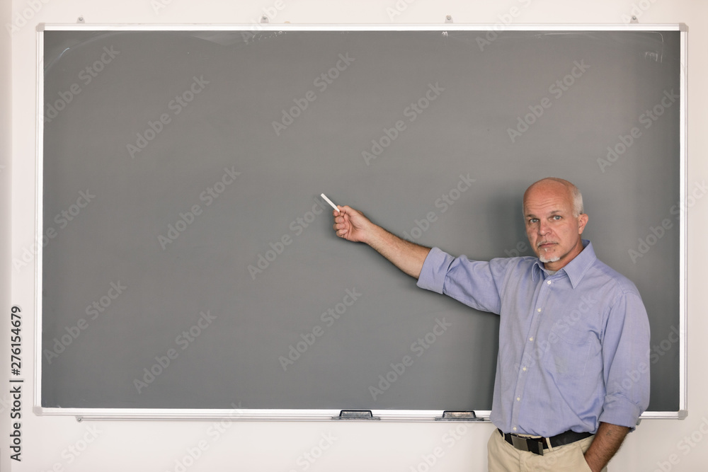 Senior teach holding chalk pointing to chalkboard Senior teach holding chalk pointing to chalkboard