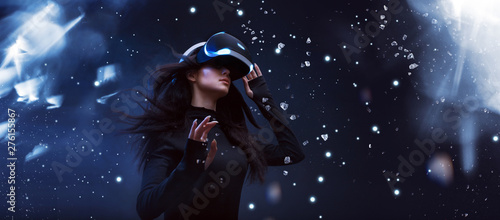 Beautiful woman with flowing hair in futuristic dress over dark background. Girl in glasses of virtual reality. Augmented reality, game, future technology concept. VR.