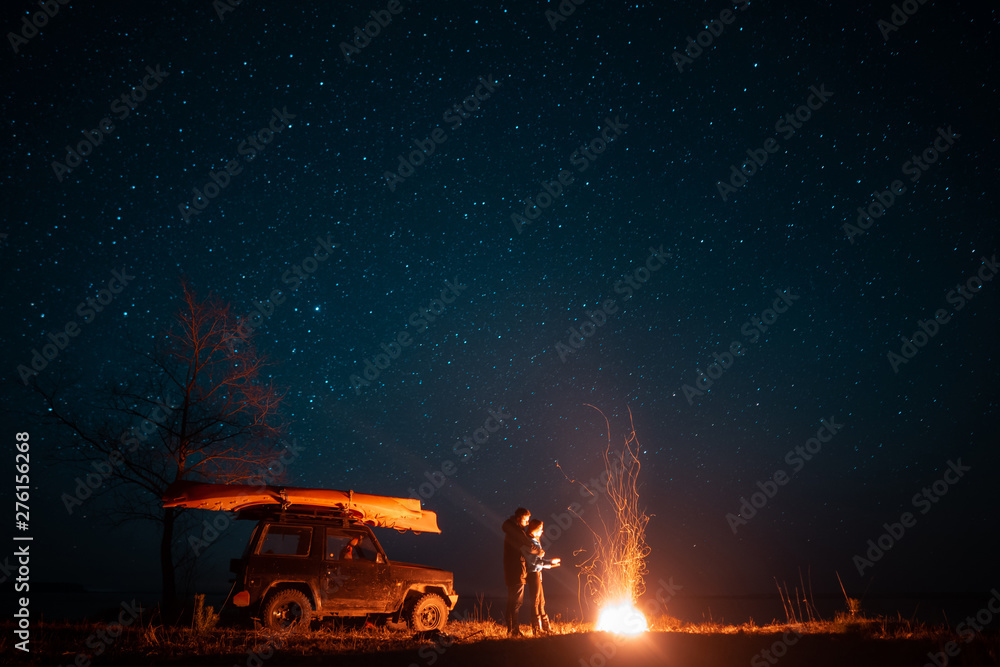 Happy couple man and woman standing in front burning bonfire Happy couple man and woman standing in front burning bonfire