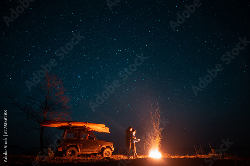 Happy couple man and woman standing in front burning bonfire