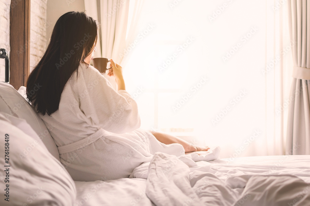 asian woman relaxing in the hotel room, drinking morning coffee, copy space - obrazy, fototapety, plakaty 