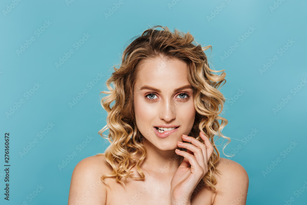 Beauty image of alluring half-naked woman with curly hair biting her lips and looking at camera