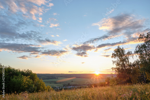 Fototapeta Naklejka Na Ścianę i Meble -  Beautiful sunset on a hill among the trees overlooking the village