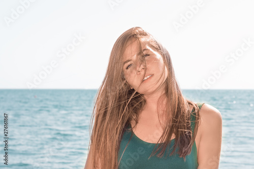 Portrait of a young beautiful girl with long hair posing in the camera against the sea