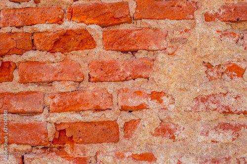 Architectural background of an aged solid construction with detailed rough surface – Bright red weathered brick wall with copy space