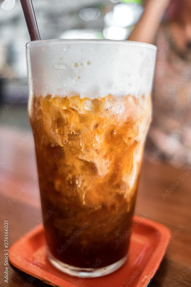 Ice coffee close-up on a wood table with cream being poured into it Ice coffee close-up on a wood table with cream being poured into it
