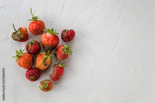 trendy ugly strawberry on a light table. Spoiled food. Natural organic food. Top view, copy space. horizontal orientation