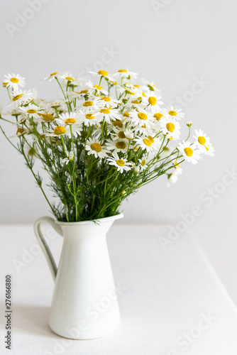 Fototapeta Naklejka Na Ścianę i Meble -  Daisy chamomile bouquet in vase on white table. Side view with copy space. Country style