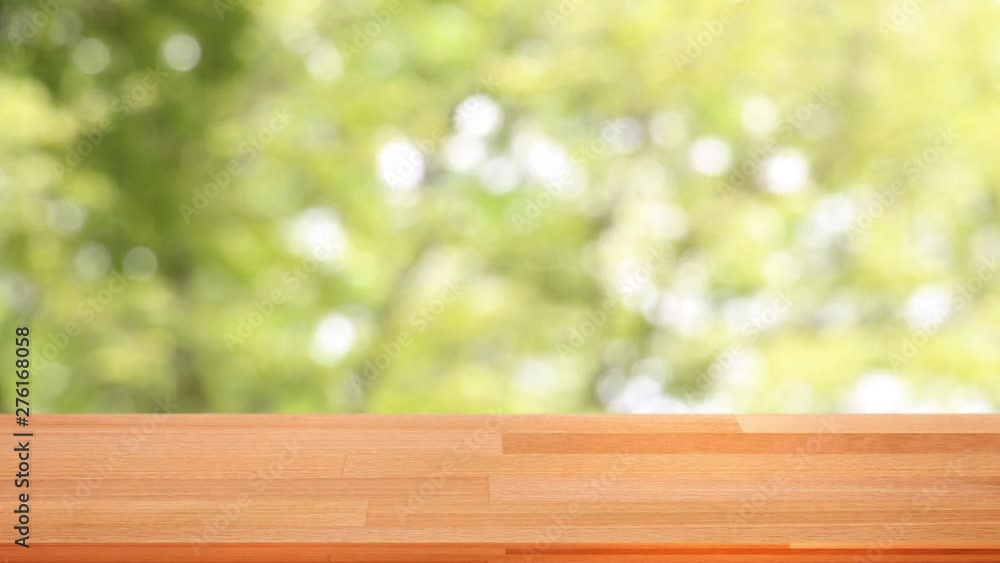 Empty wooden table template on top with nature green background moving with windy across swaying trees for montage of your product on table.