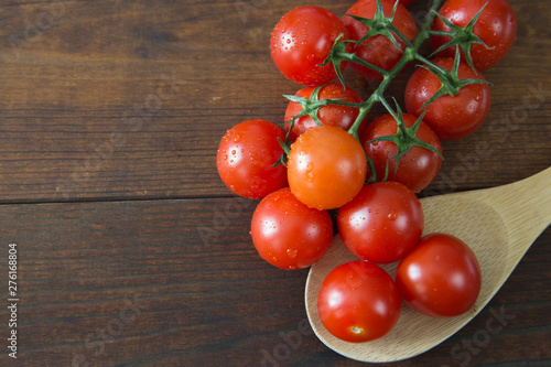 Fresh cherry tomatoes on wooden background with wooden ladle