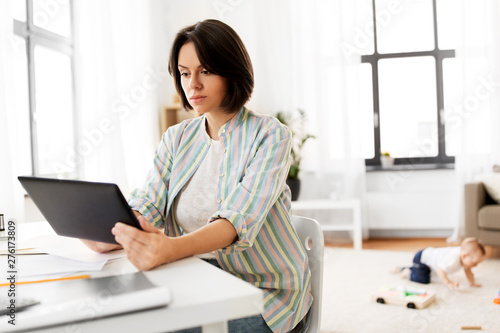 multi-tasking, freelance and motherhood concept - working mother with tablet pc computer and baby boy playing at home