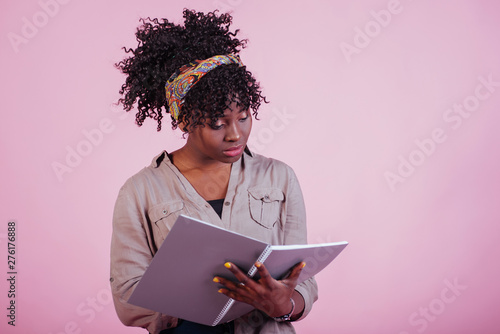 Preparing for exam. Attractive afro american woman in casual clothes at pink background in the studio