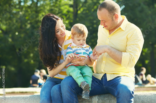 outdoor portrait of a family. young parents with a baby for a walk in the summer park. Mom, dad and child