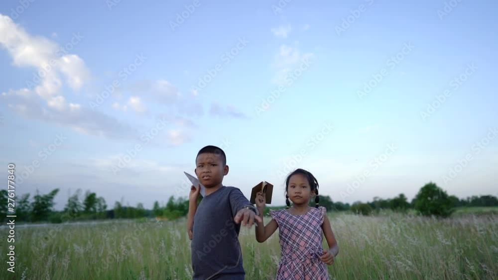 Slow Motion, Asian brothers and sisters, brothers and sisters playing a paper plane together happily in the grasslands Slow Motion, Asian brothers and sisters, brothers and sisters playing a paper plane together happily in the grasslands