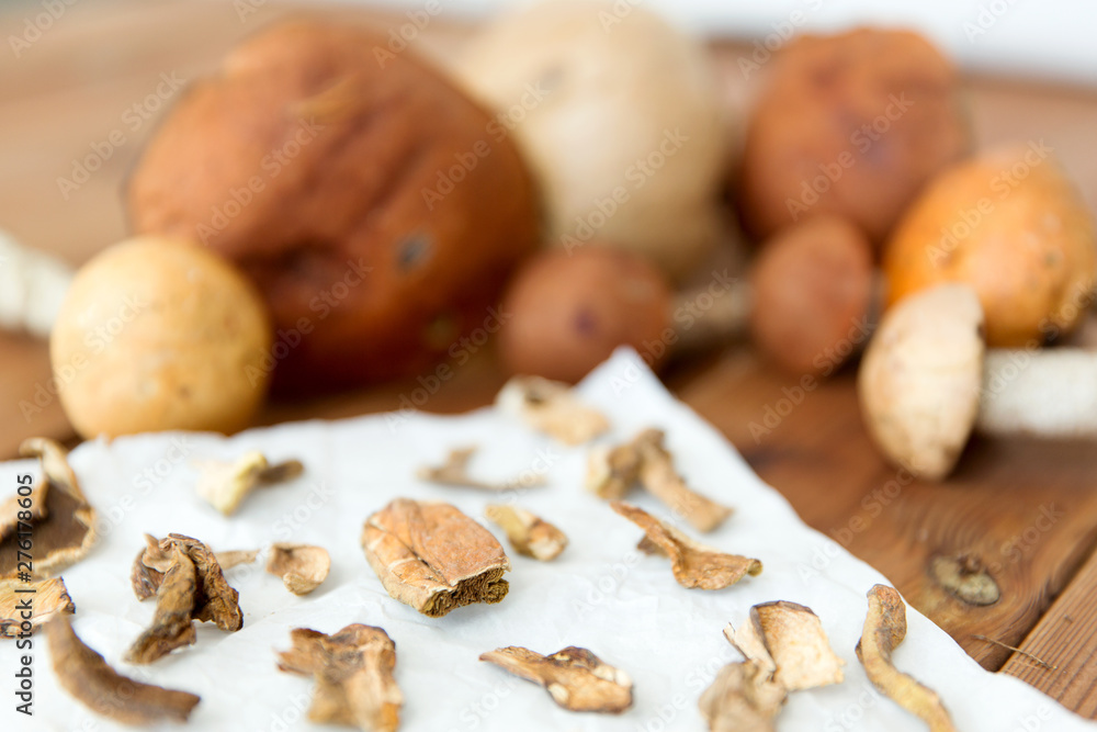 culinary, food and cooking concept - dried mushrooms on baking paper on wooden background culinary, food and cooking concept - dried mushrooms on baking paper on wooden background