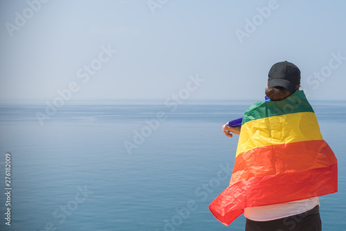 Young girl from behind, holding a banner looking at the sea