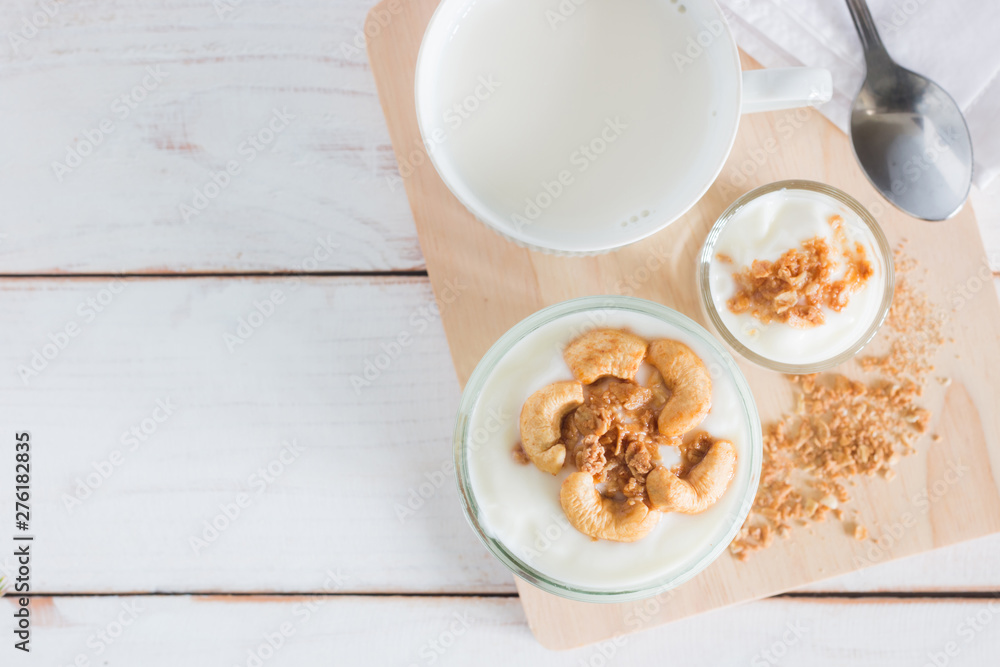 Healthy meal made of granola in glass, Yogurt and cornflakes Decorate food with Cashew Nut with hot milk setting on white wooden table, healthy care concept, copy space