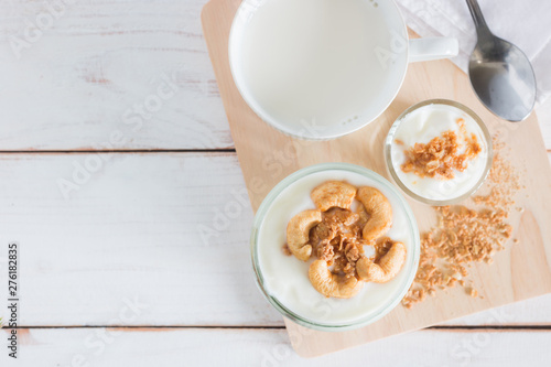 Healthy meal made of granola in glass, Yogurt and cornflakes Decorate food with Cashew Nut with hot milk setting on white wooden table, healthy care concept, copy space