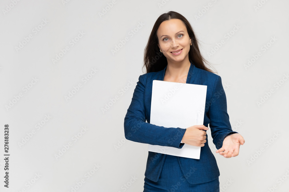 Portrait of a young pretty brunette manager woman of 30 years in a business blue suit with beautiful dark hair. Standing with a folder on a white background, talking, showing hands, with emotions Portrait of a young pretty brunette manager woman of 30 years in a business blue suit with beautiful dark hair. Standing with a folder on a white background, talking, showing hands, with emotions