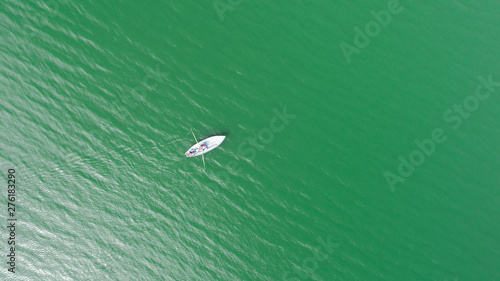 Aerial view of couple on rowboat having fun on beautiful lake with green water at summer vacation